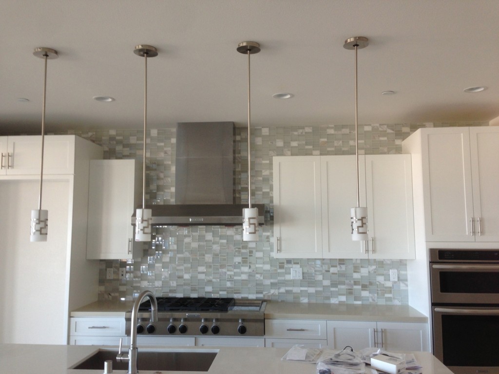 brushed nickle and white glass pendant lights illuminate the kitchen island