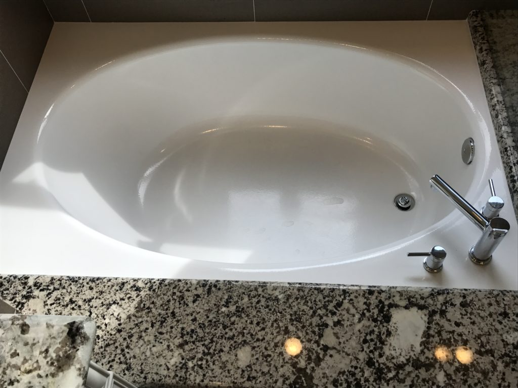 bathroom contractor uses black granite and white soaking tub to provide modern look in remodel