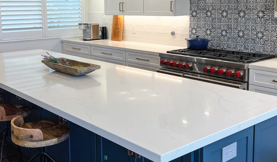 Spanish inspired kitchen renovation with white and blue cabinetry, wood accents, and Spanish style backsplash