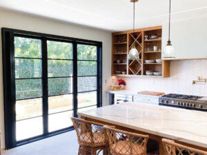 After kitchen remodeler adds open shelves storing white cups and plates