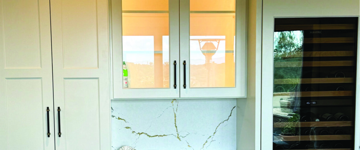 White built-in cabinetry with wine fridge, Cambria quarta countertops, in-cabinet lighting, and dark hardware