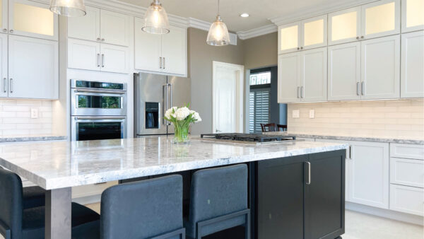 Black kitchen island with seating and white perimeter cabinets with Cambria quartz countertops