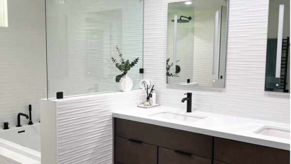 Master bathroom with white patterned tile on walls, white countertops, and dark wood toned cabinets