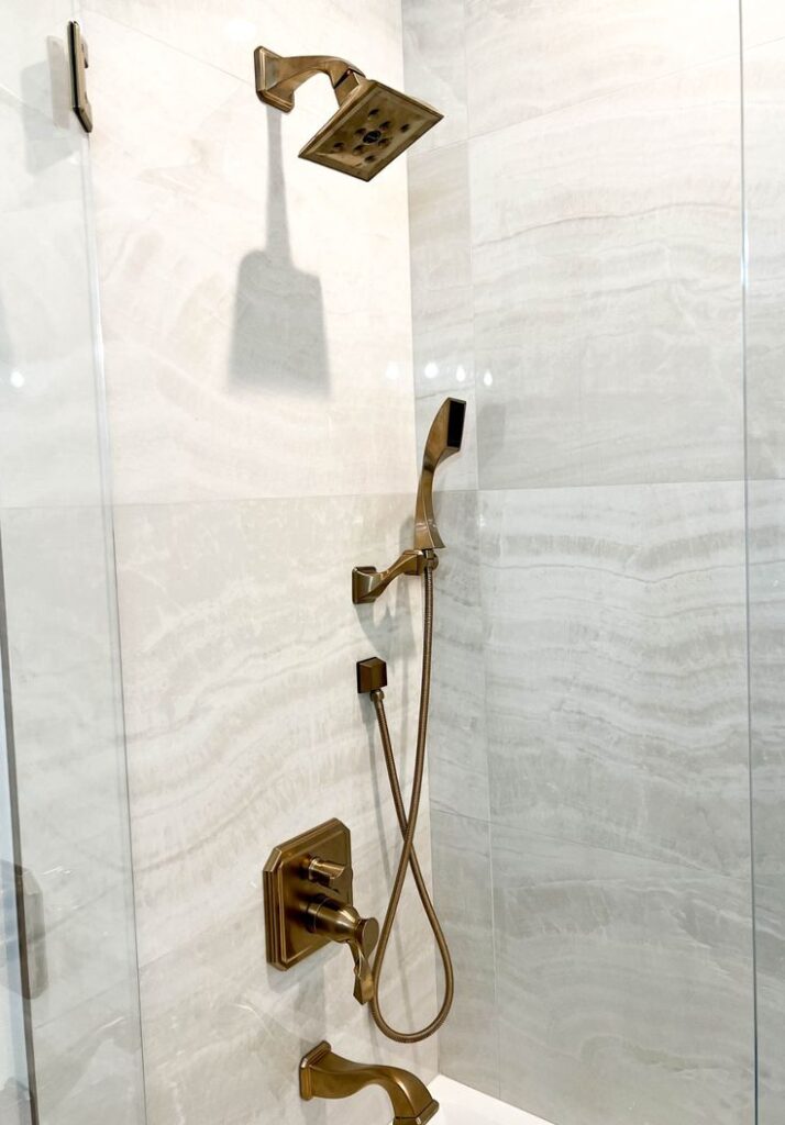 Orange County shower remodel after photo with white tile and bronze rainshower head and adjustable handheld shower head